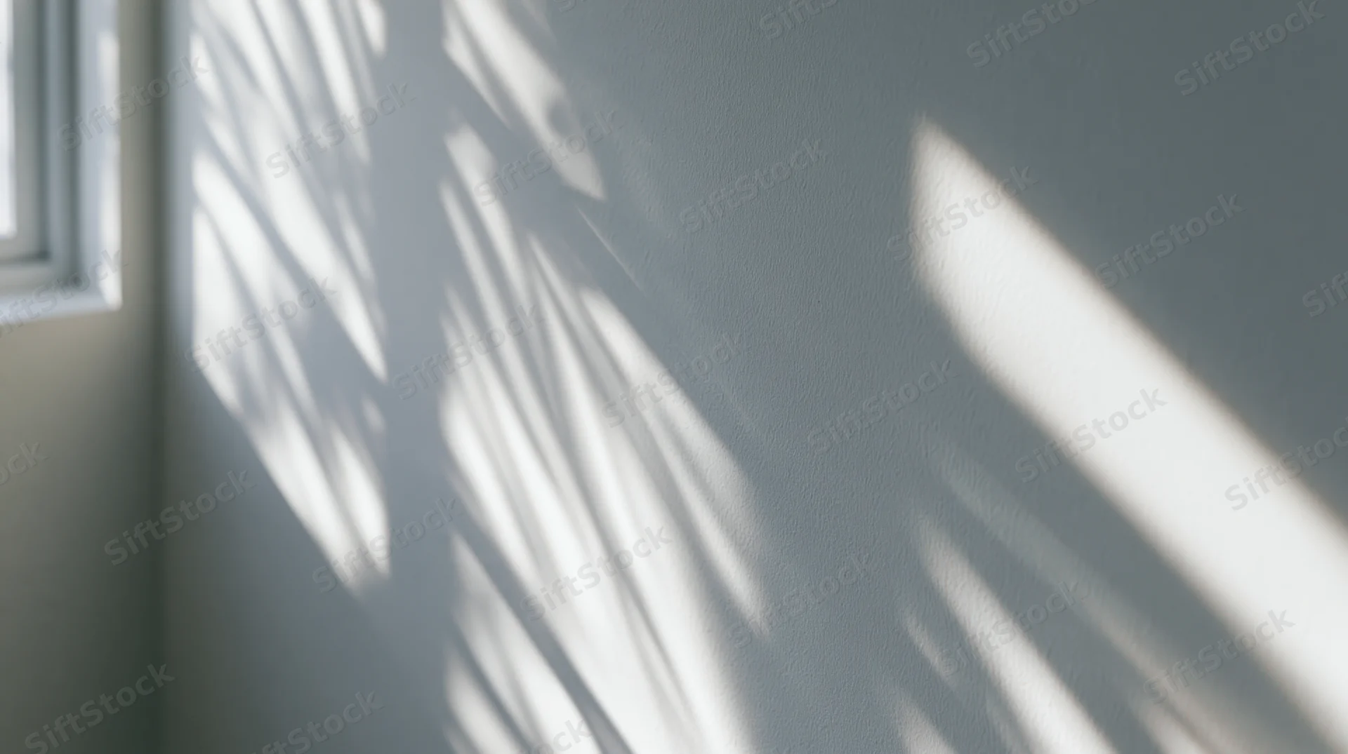 Sunlight filtering through blinds casting striped shadows on a gray wall in a quiet room