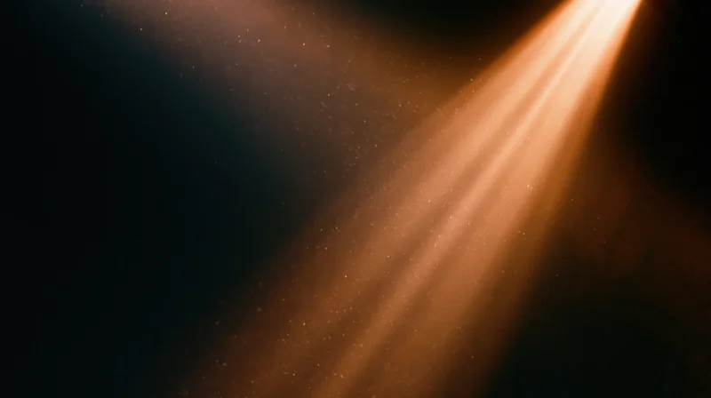 Warm sunbeams cutting through dust in a dark room, creating glowing rays of light