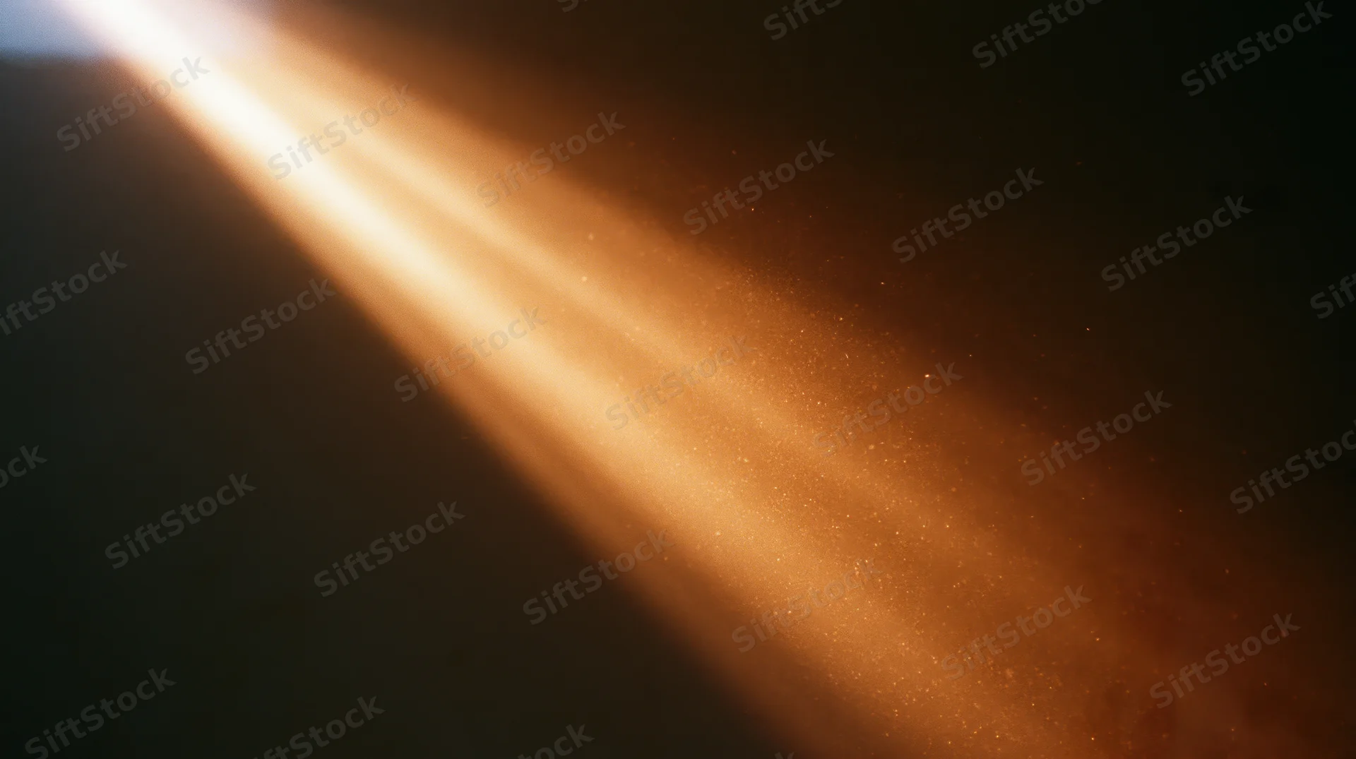 Golden sunbeam cutting through dust particles in a dark room, creating a glowing path of light