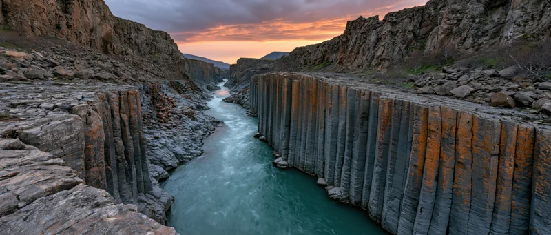 Turquoise river flowing through basalt columns in a narrow canyon at sunset