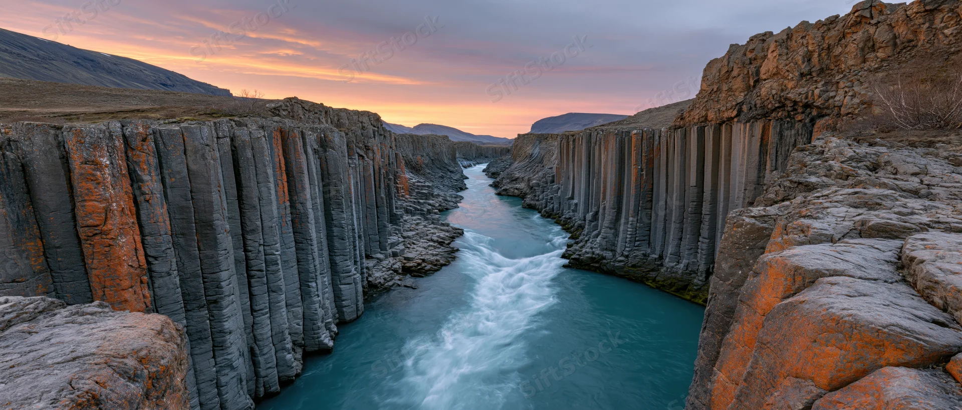 Turquoise river flowing through basalt columns in a canyon at sunset