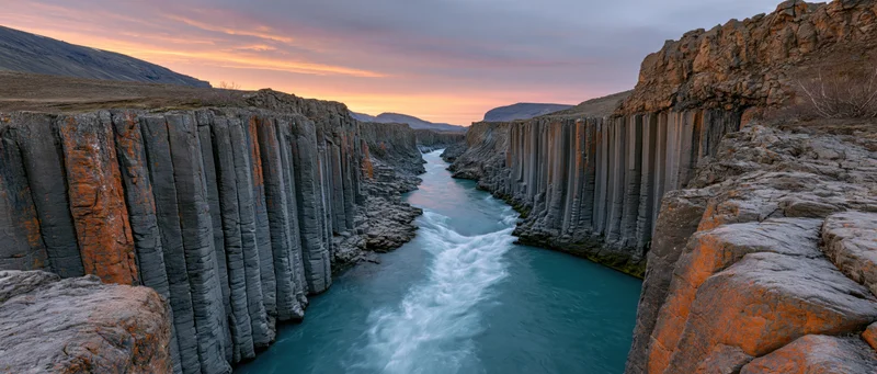 Turquoise river flowing through basalt columns in a canyon at sunset