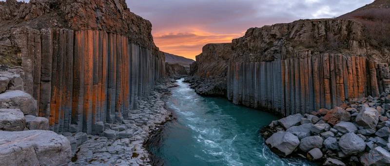 Turquoise river flowing through basalt columns in a canyon at sunset