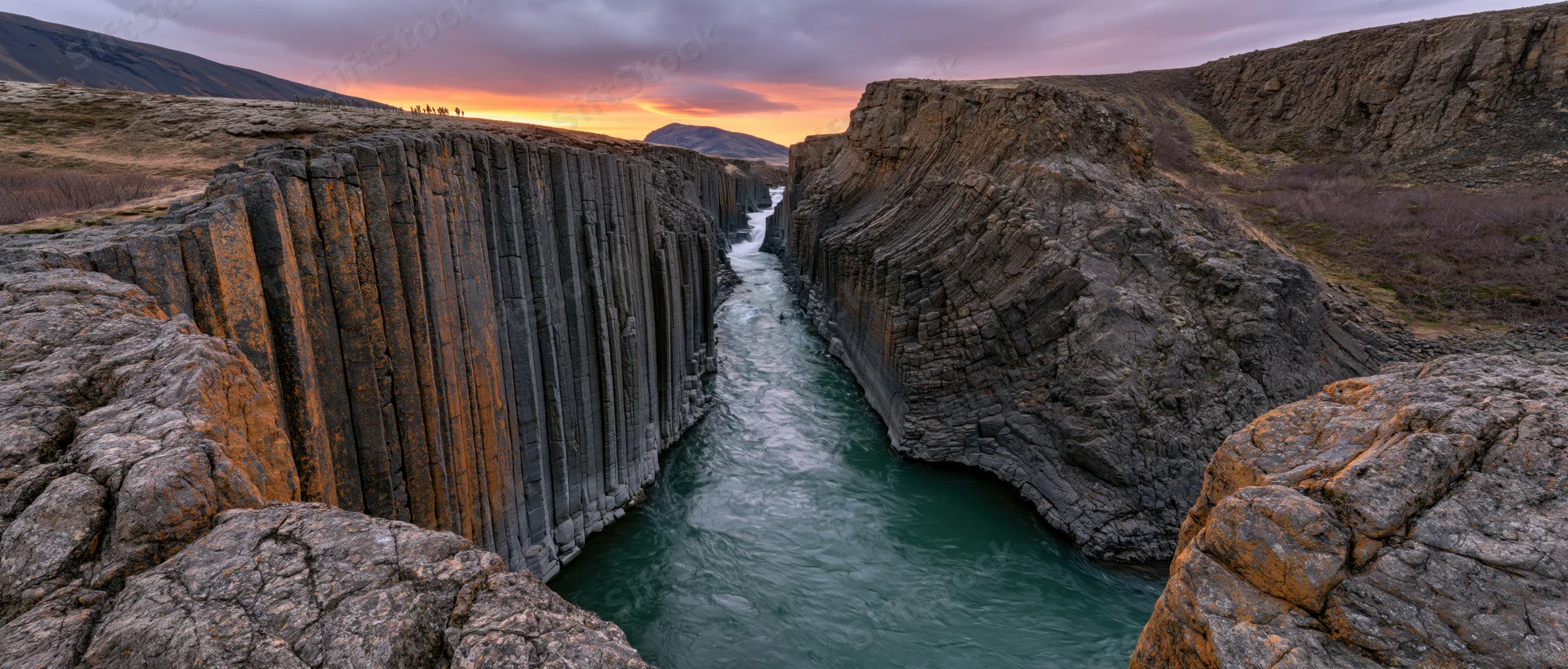 River flowing through columnar basalt canyon at sunset