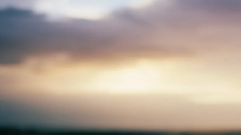 Blurred sky with soft clouds at sunset showing warm gradient colors across the horizon