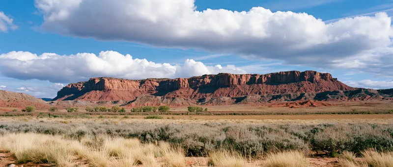 Red rock canyon formation under cloudy blue sky in arid desert landscape