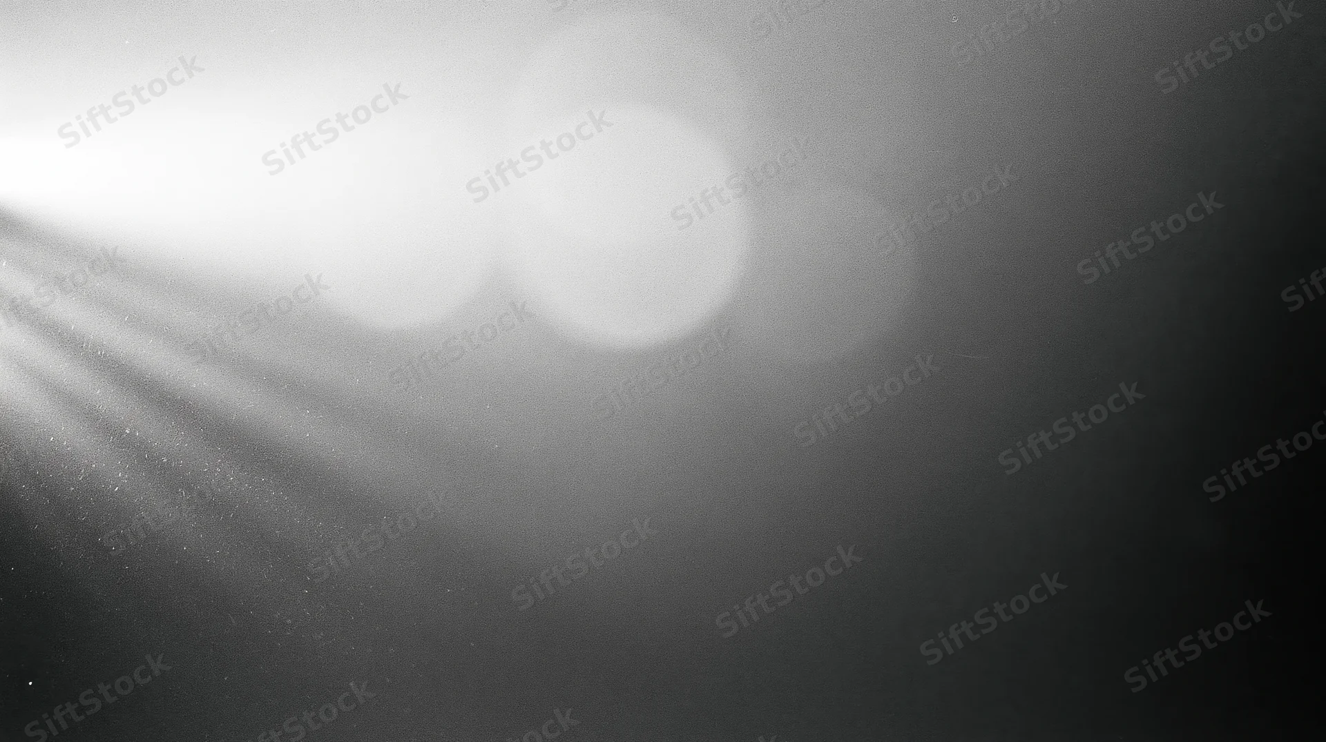 Soft light beams and bokeh circles in a monochrome abstract background with copyspace