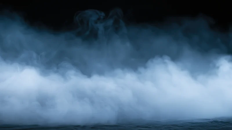 Swirling white smoke rising from dark water surface at night
