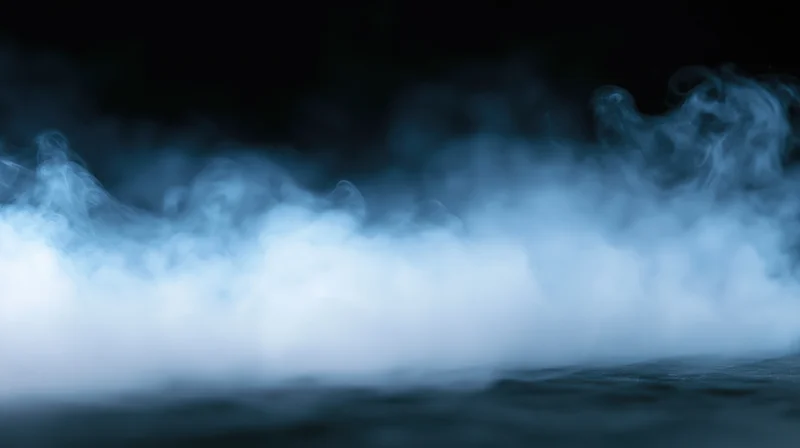 Swirling blue smoke rising from a dark surface in low light