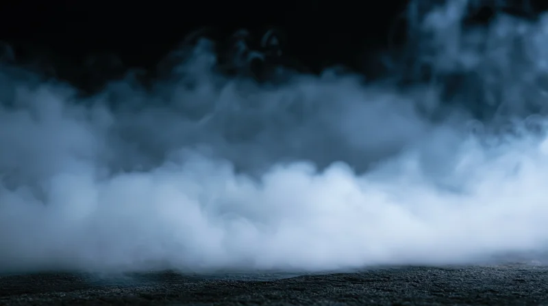 Swirling white smoke rising from a dark textured surface at night
