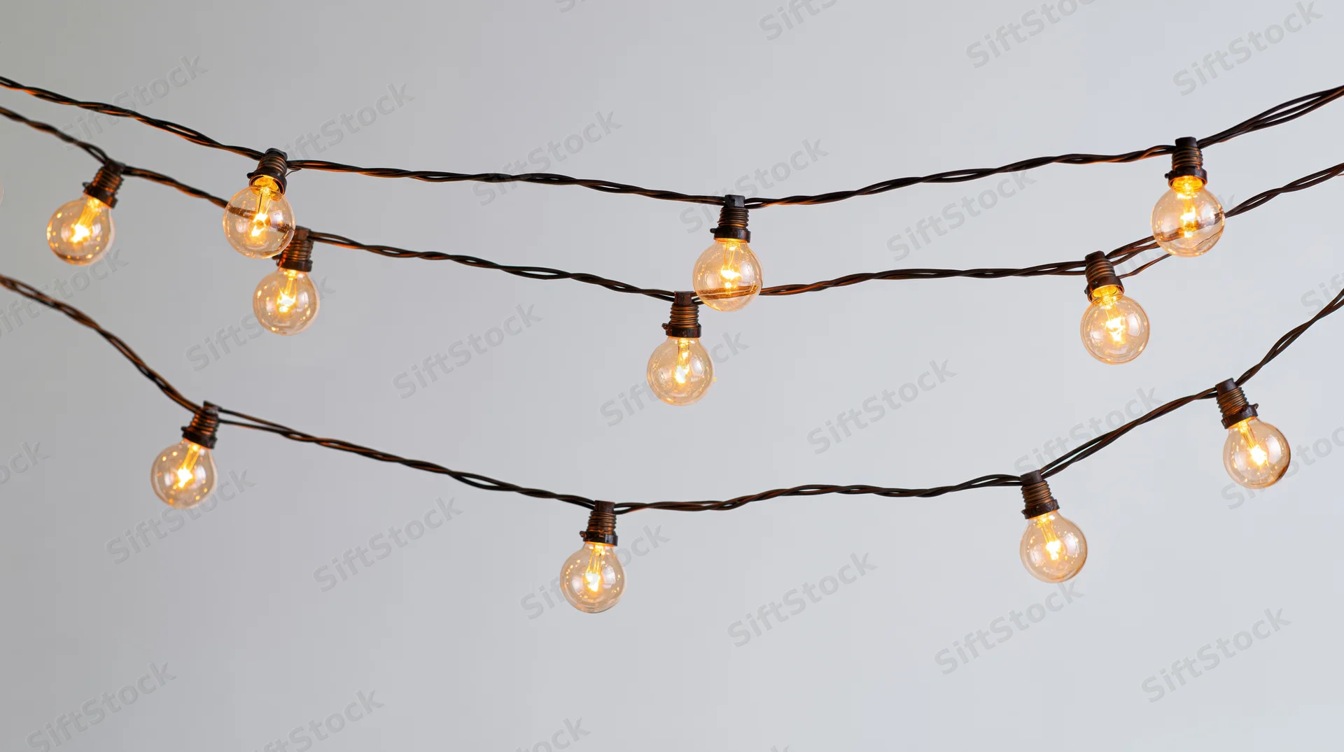String lights with warm glowing bulbs arranged in parallel rows against a plain background
