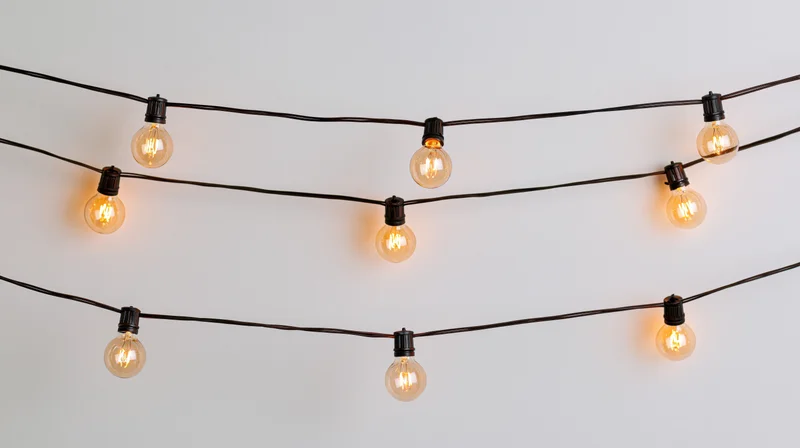 String lights with warm glowing bulbs arranged in parallel rows against a plain white wall
