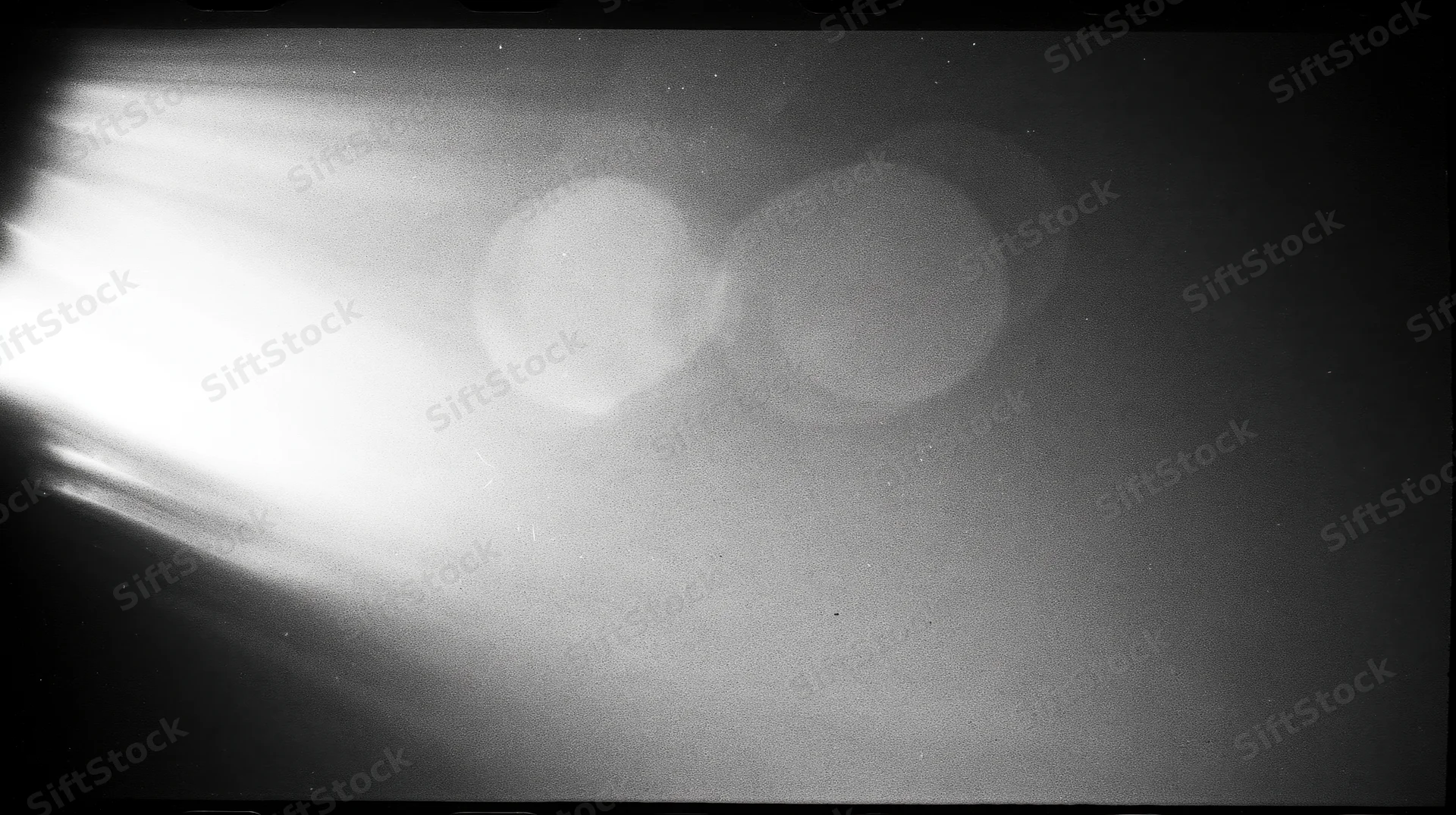 Bright light flare with circular bokeh effects in a dark monochrome frame