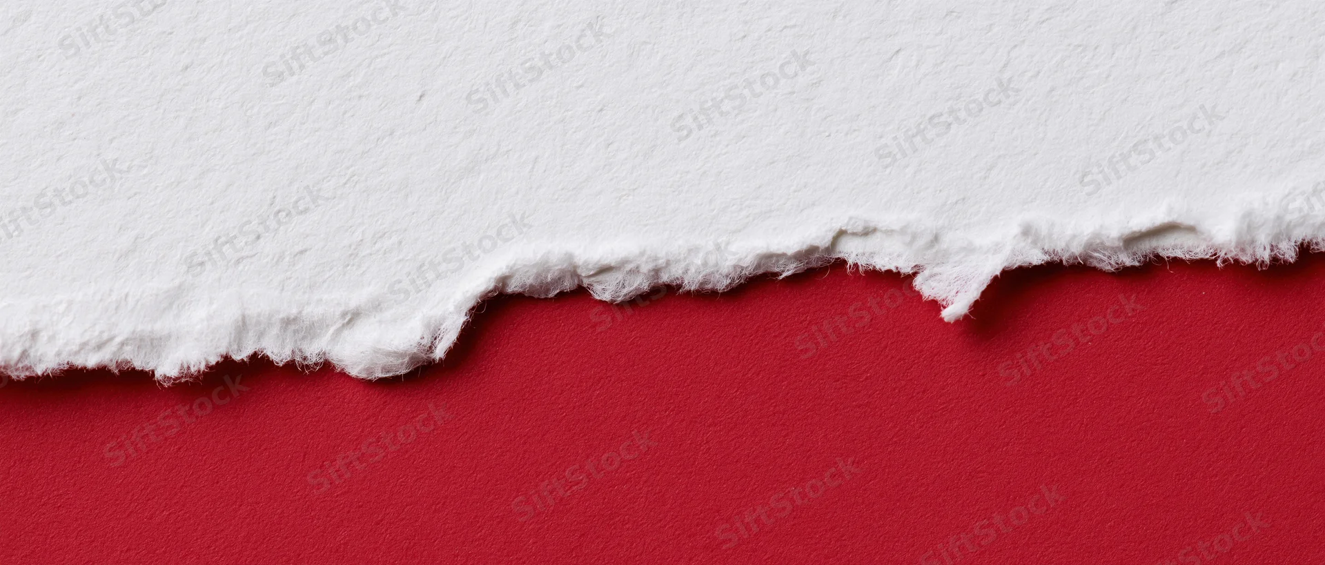 Torn white paper revealing red background with textured edge