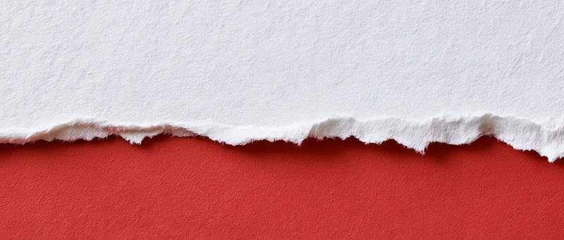 Torn white paper revealing red surface below