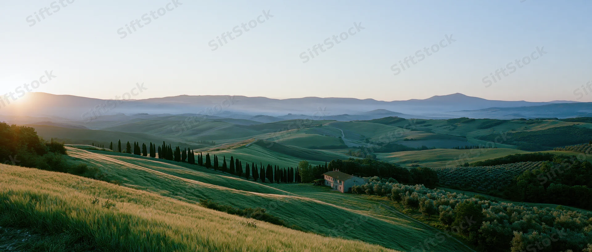 Rolling green hills with a farmhouse and cypress trees at sunset in tuscany