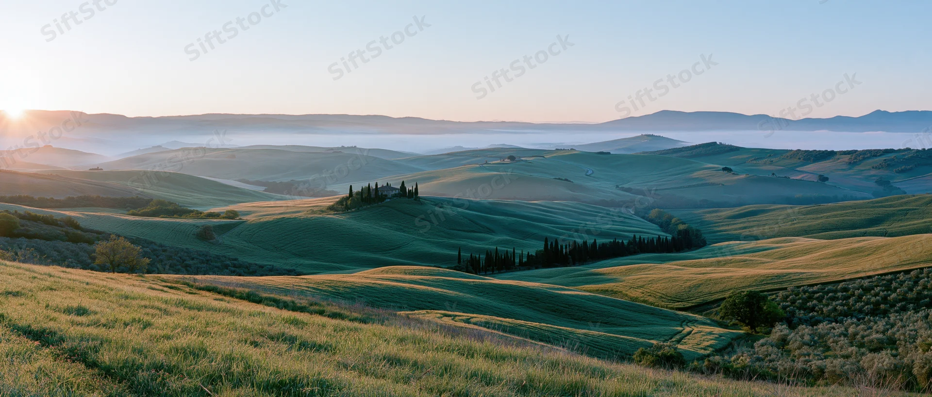 Rolling green hills with cypress trees and farmhouses at sunrise in tuscany