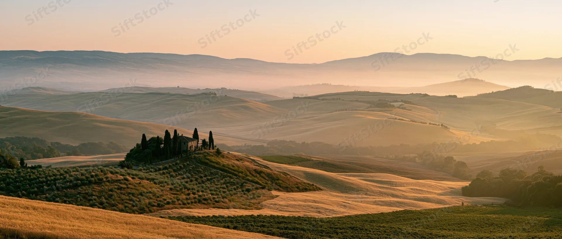 A stone villa with cypress trees atop a hill in the tuscan countryside at sunrise