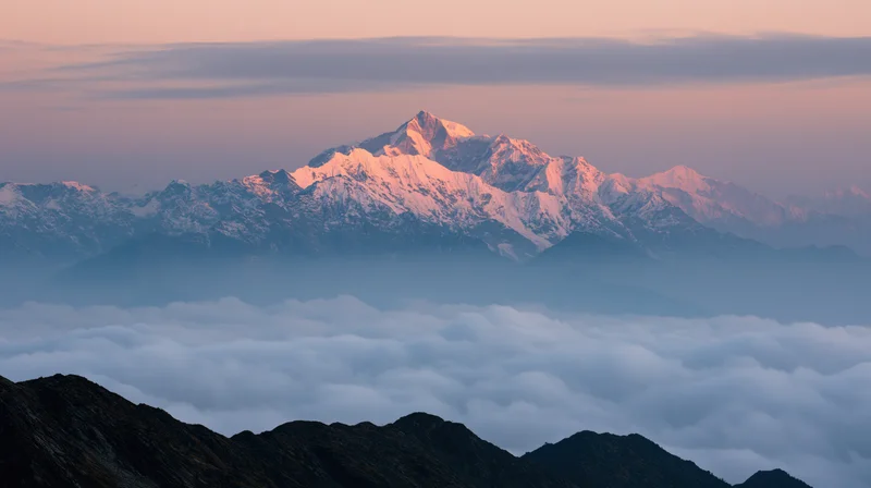 Snow-covered mountain peaks rising above a sea of clouds at sunrise