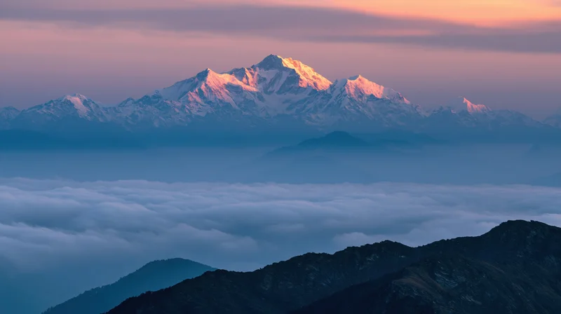 Snow-capped mountain peaks rising above a sea of clouds at sunrise