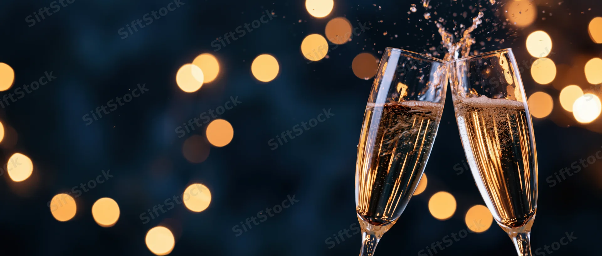 Two champagne glasses clinking together with bubbles and sparkles against a dark background with golden bokeh lights