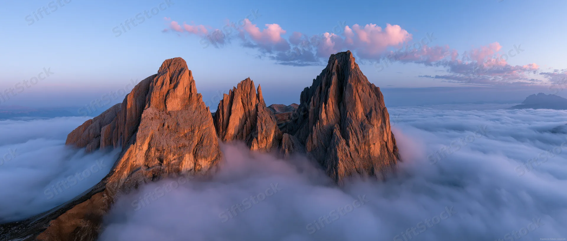 Jagged mountain peaks rising above a sea of clouds at sunrise