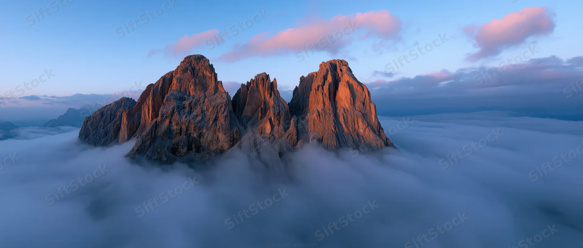 Rugged mountain peaks rising above a sea of clouds at sunrise