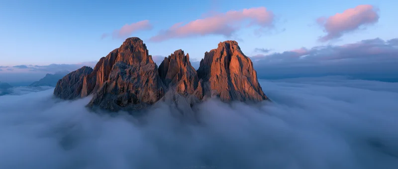 Rugged mountain peaks rising above a sea of clouds at sunrise