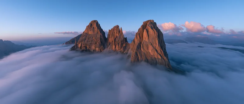 Jagged mountain peaks rising above a sea of clouds at sunrise