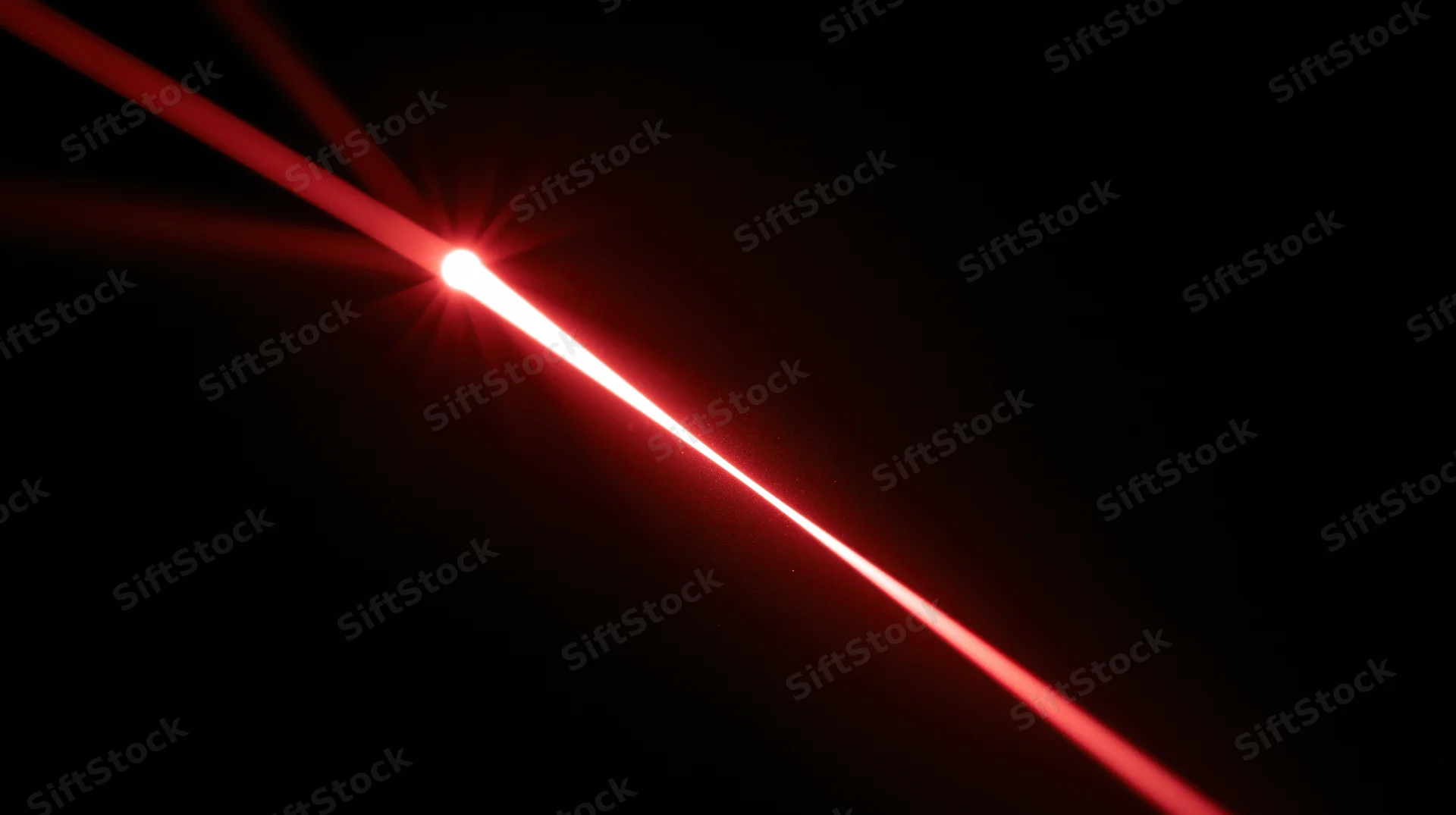 Red laser beam emitting from a source in a dark environment