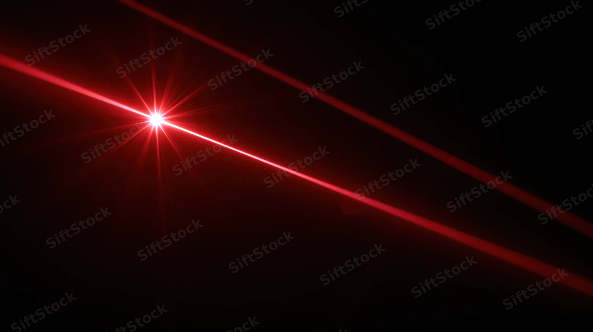 Red laser beam emitting bright starburst light in dark space