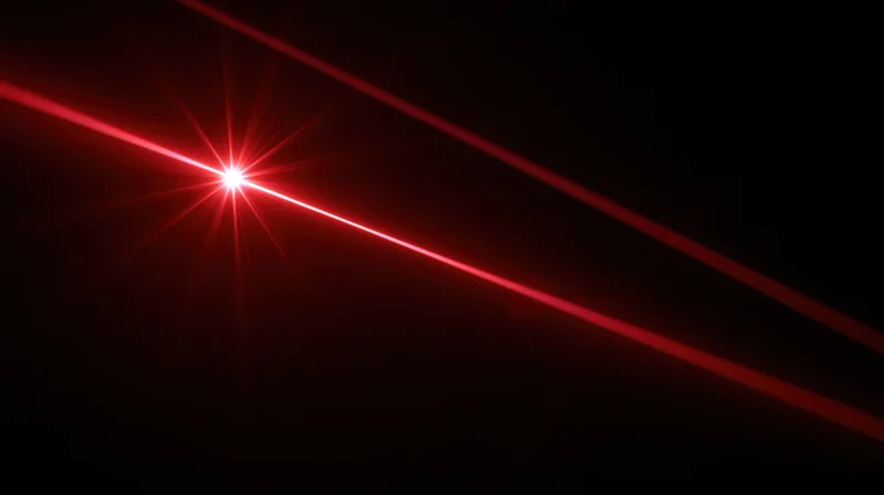Red laser beam emitting bright starburst light in dark space