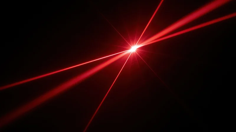 Red laser beams converging at a bright focal point in darkness