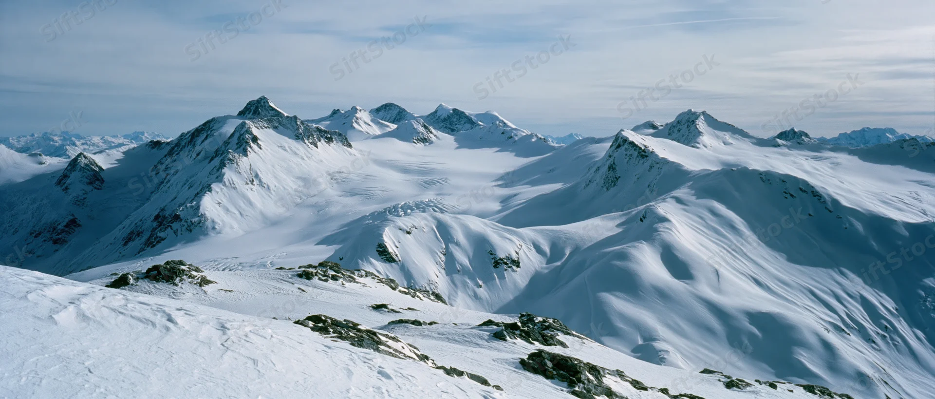 Snow-covered mountain peaks and glaciers in alpine terrain under clear sky