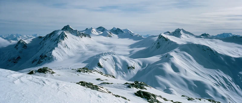 Snow-covered mountain peaks and glaciers in alpine terrain under clear sky