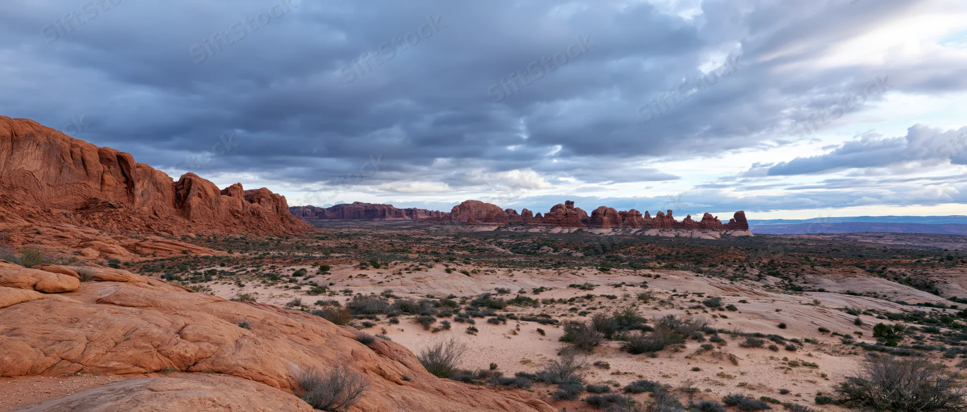 Red rock formations in a vast desert landscape under an overcast sky