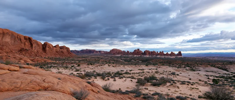 Red rock formations in a vast desert landscape under an overcast sky
