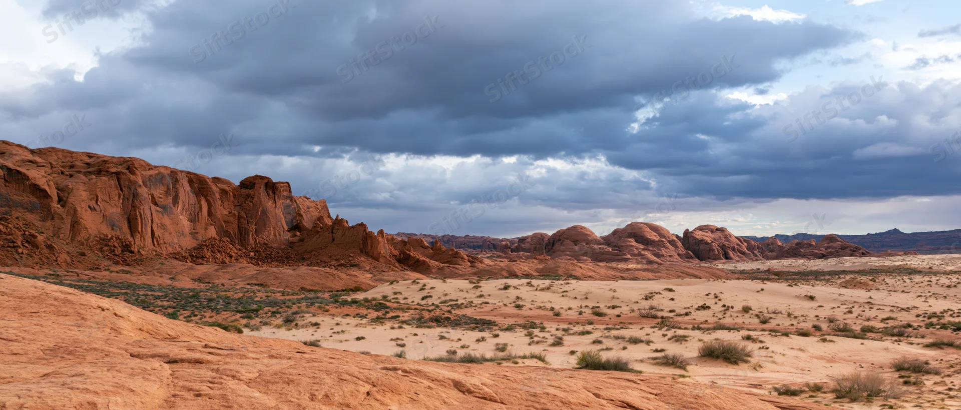 Red rock formations in a desert landscape under stormy clouds at dusk