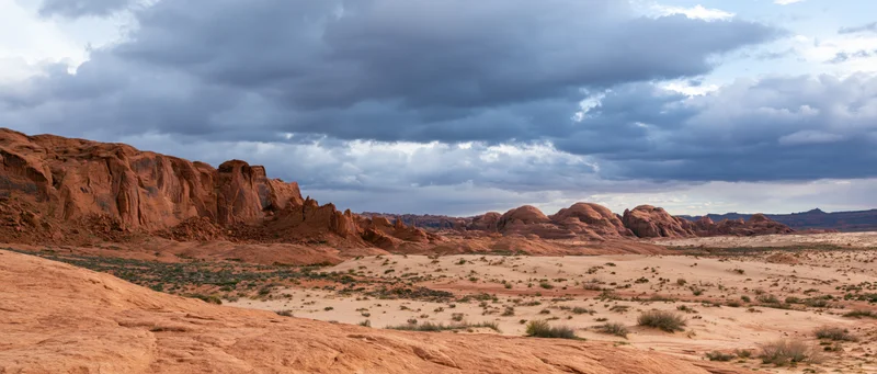 Red rock formations in a desert landscape under stormy clouds at dusk