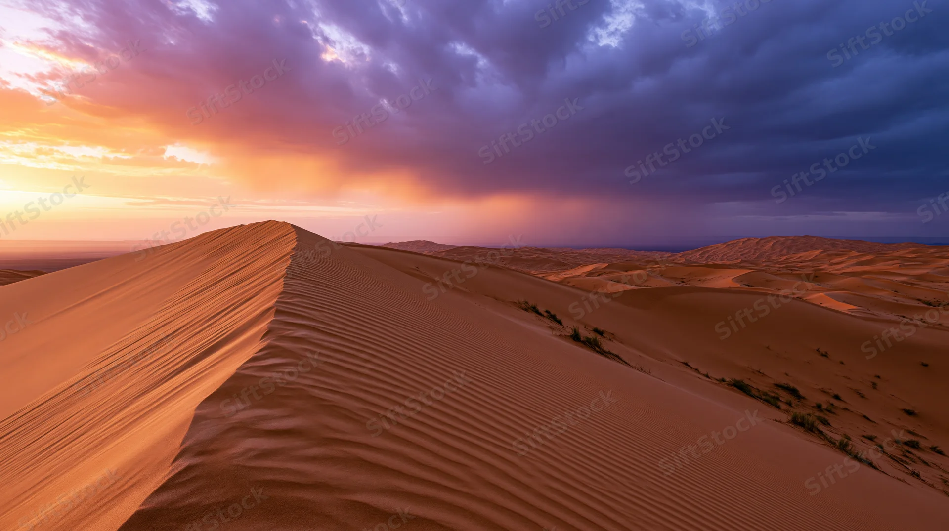 Sand dunes with rippled texture under a stormy sunset sky in a vast desert landscape