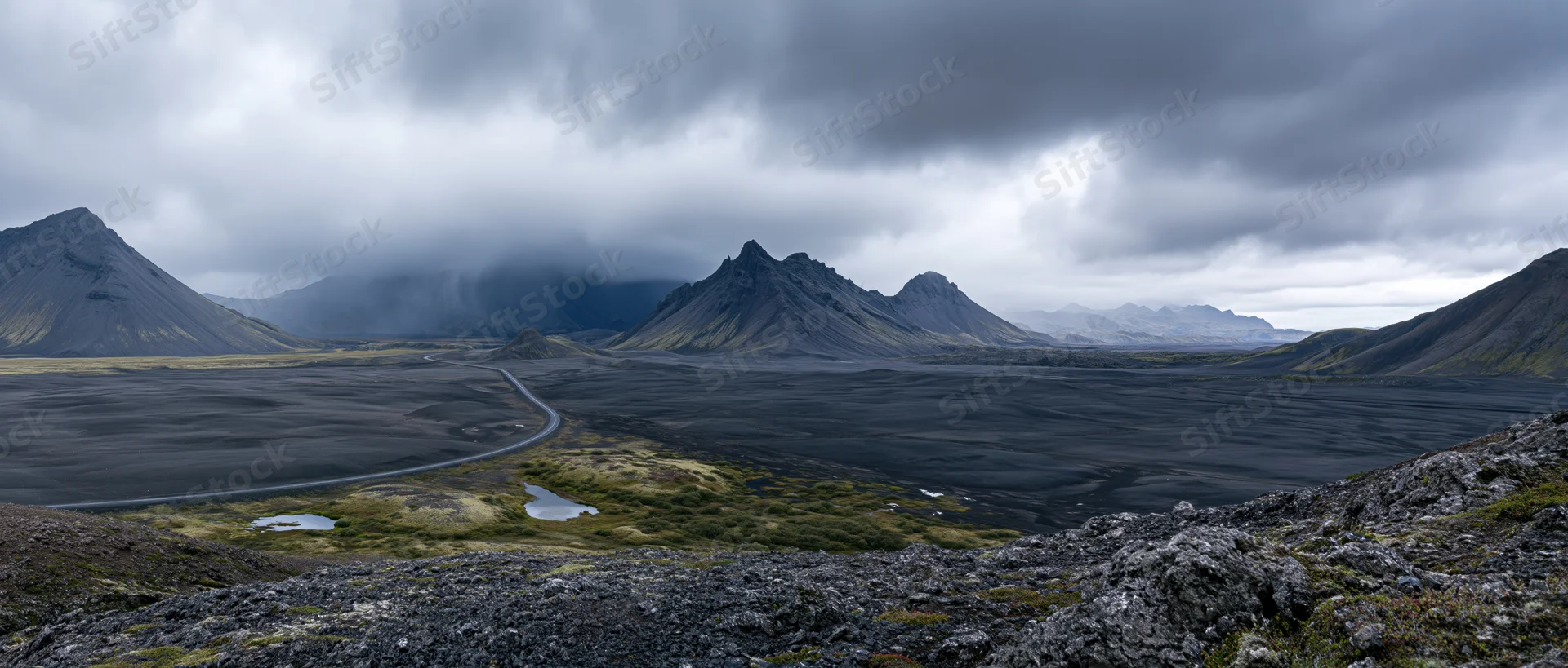 Volcanic landscape with winding road through black lava field under cloudy sky in Iceland