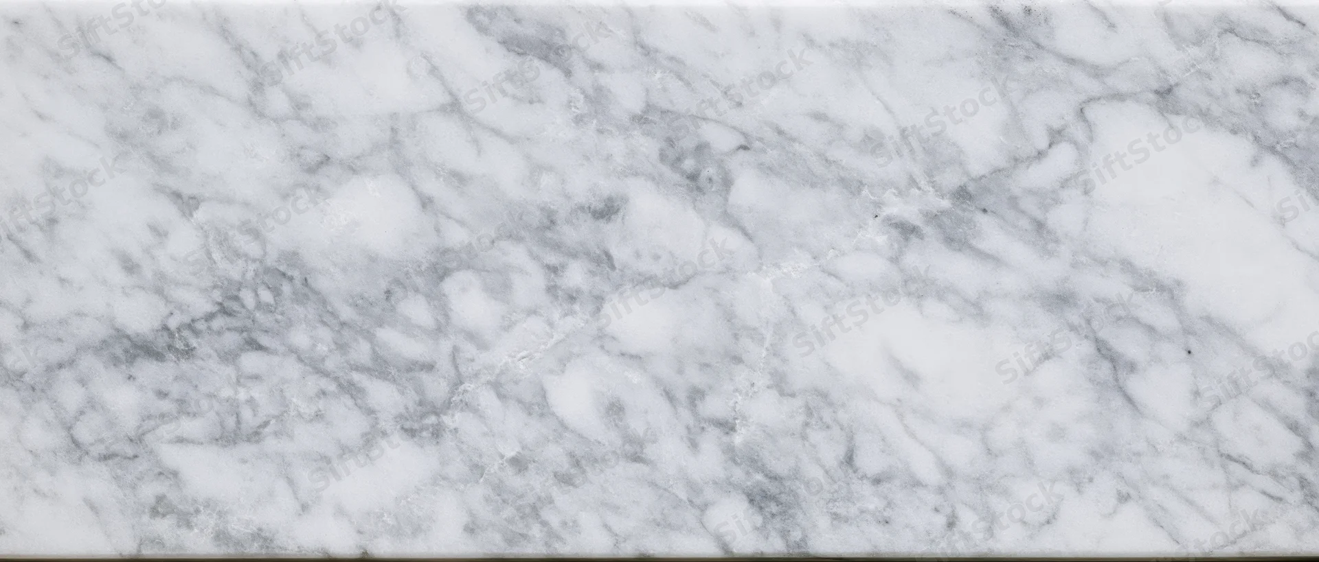 Close-up of white marble slab with gray veining, used for interior surfaces