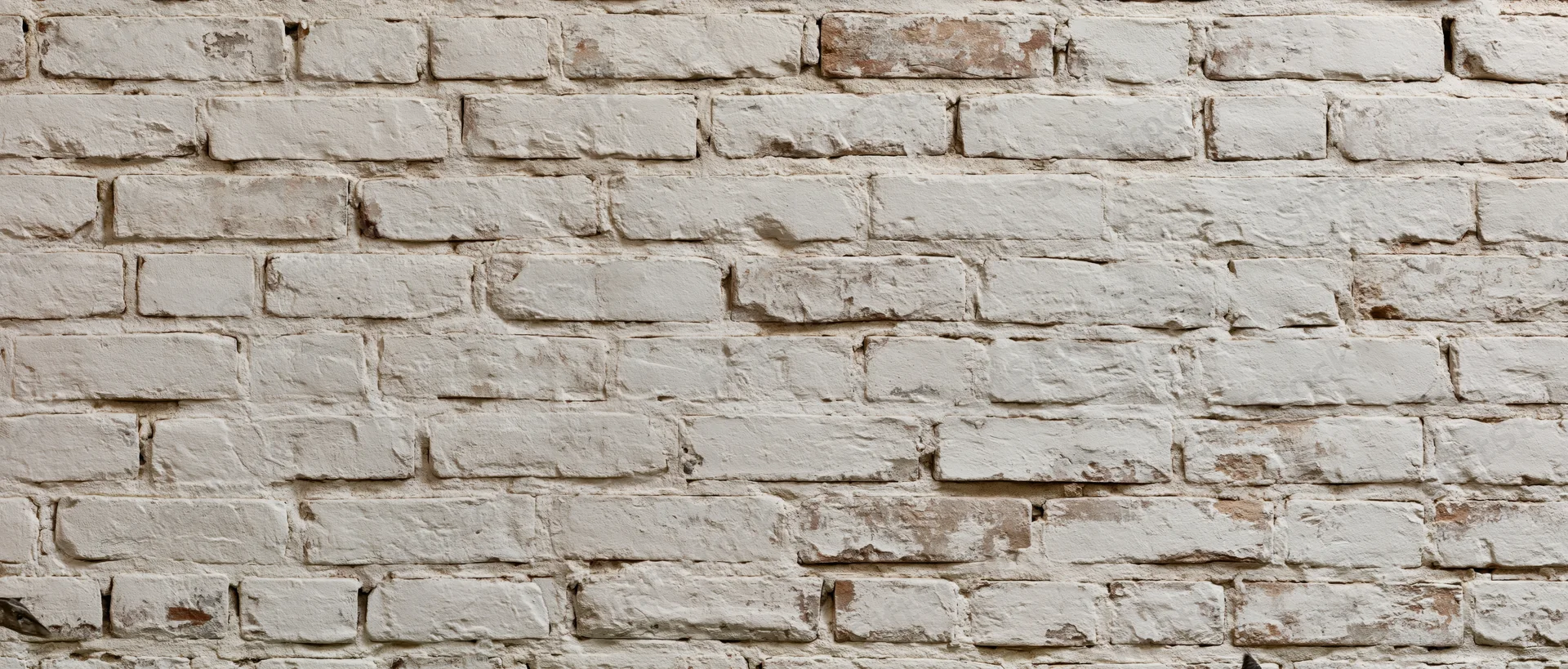 White painted brick wall with weathered texture and peeling paint showing aged mortar joints