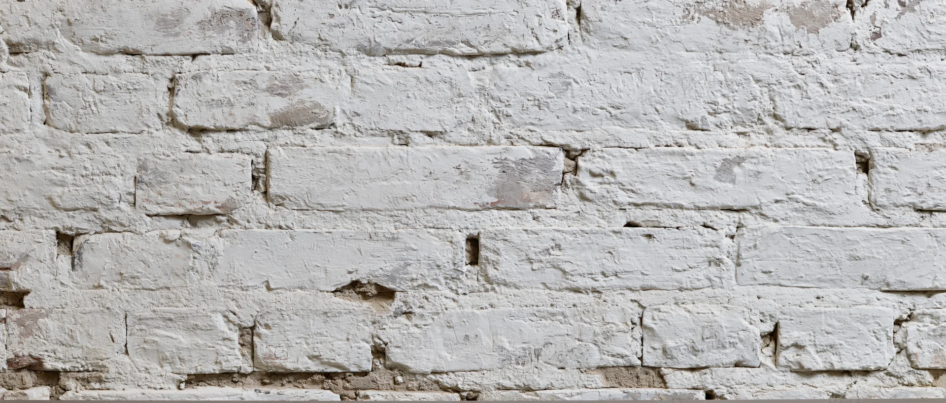 White painted brick wall with visible mortar and cracks, showing aged texture and rustic character