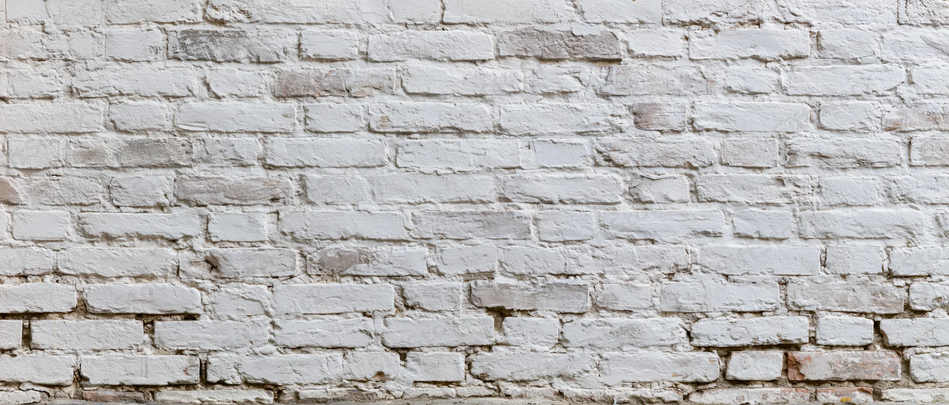 White painted brick wall with weathered texture and visible mortar joints