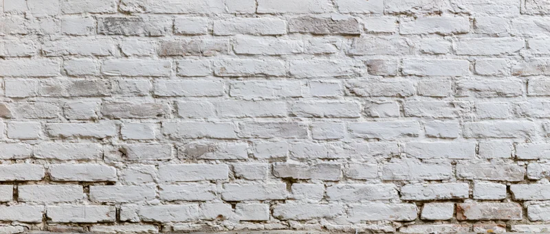 White painted brick wall with weathered texture and visible mortar joints