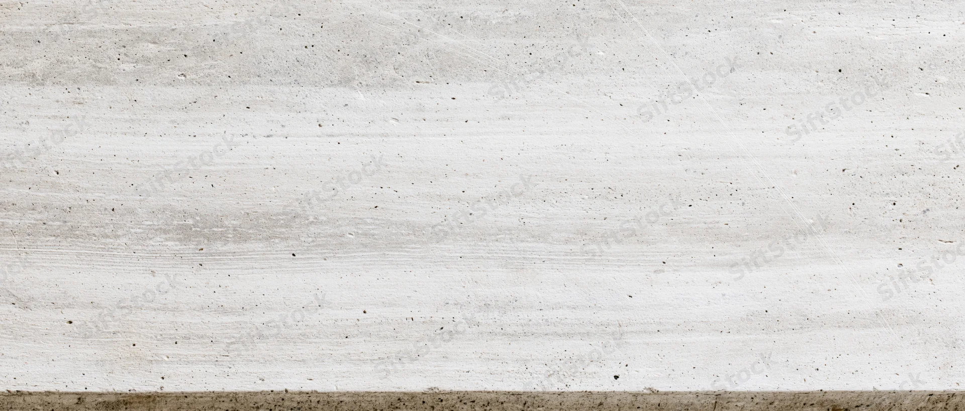 Horizontal concrete wall surface with visible texture and striations, showing aggregate and grainy finish