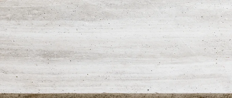 Horizontal concrete wall surface with visible texture and striations, showing aggregate and grainy finish