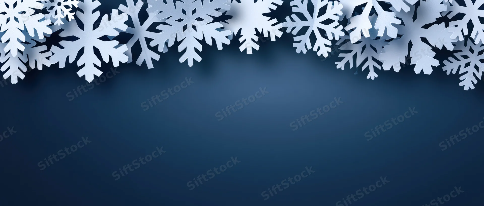 White paper snowflakes arranged as a decorative border along the top of a blue background with copyspace below