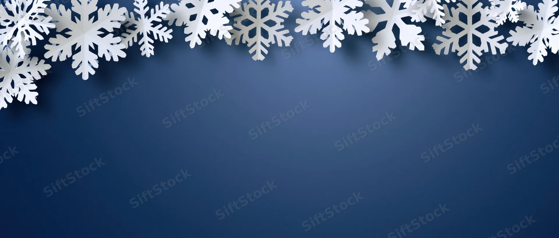 White paper snowflakes arranged along the top edge of a blue background with copyspace below